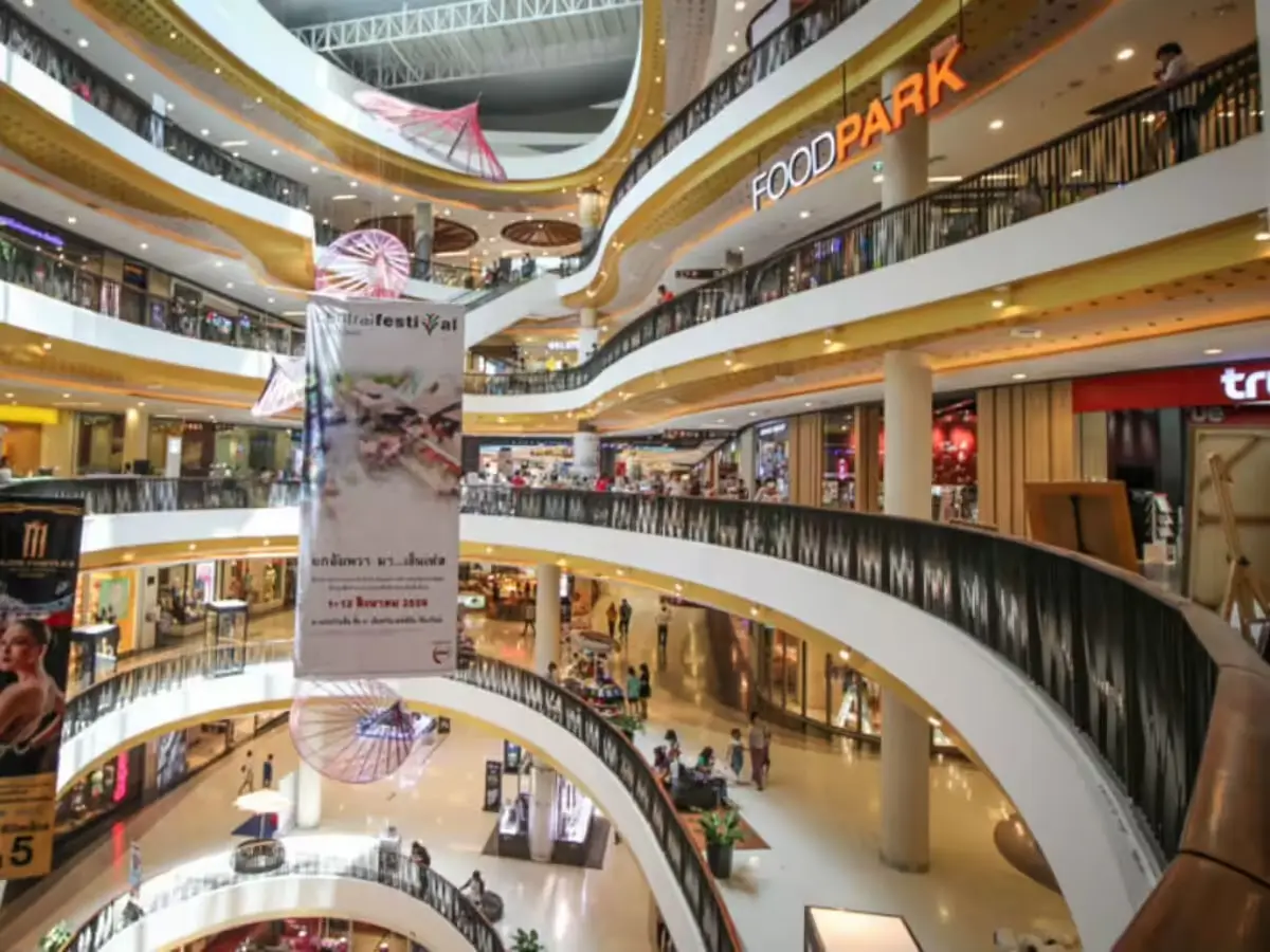 Curved balconies of a multi-storey mall atrium lined with shops and a food court sign.