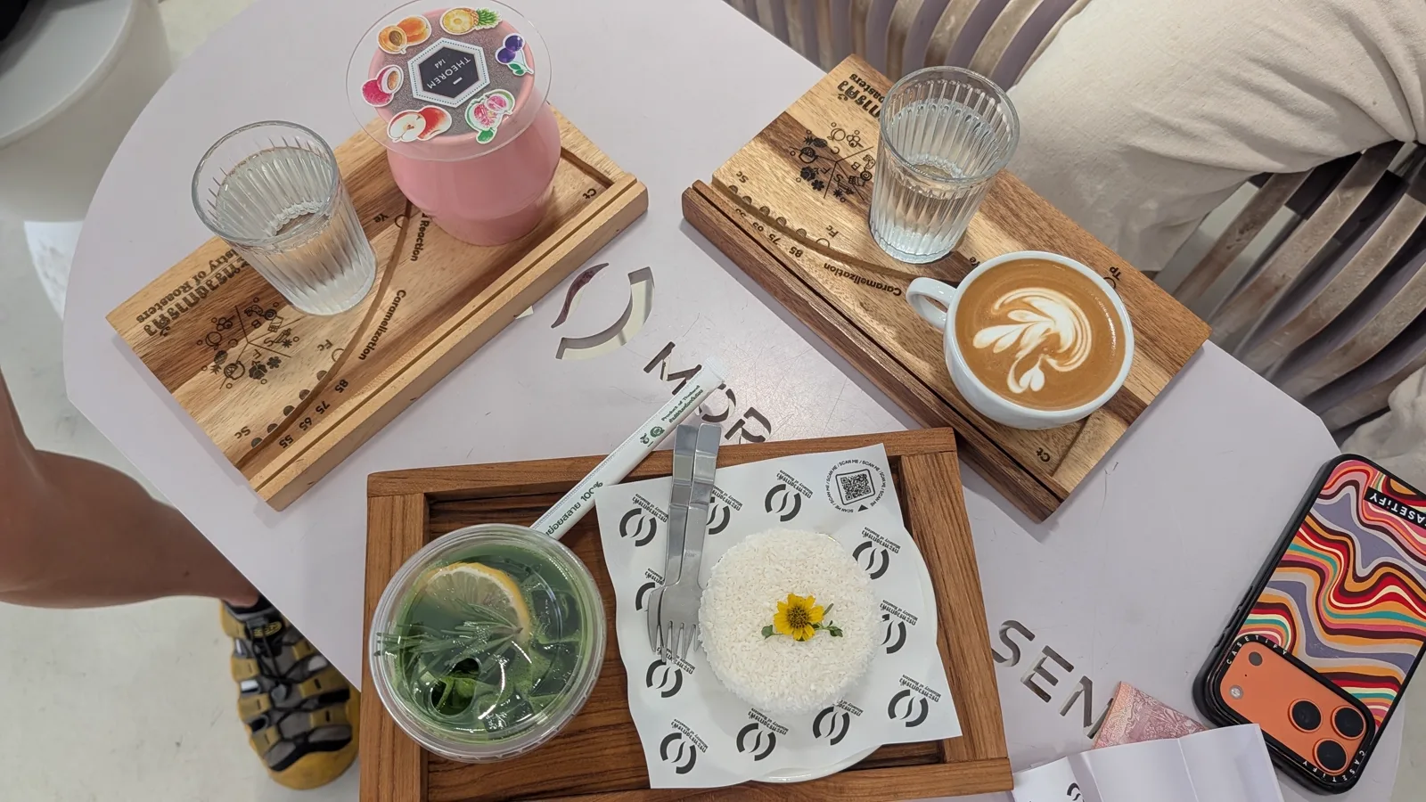 Overhead drinks and a rice dish on a tray, with MOR lettering cut into the white table