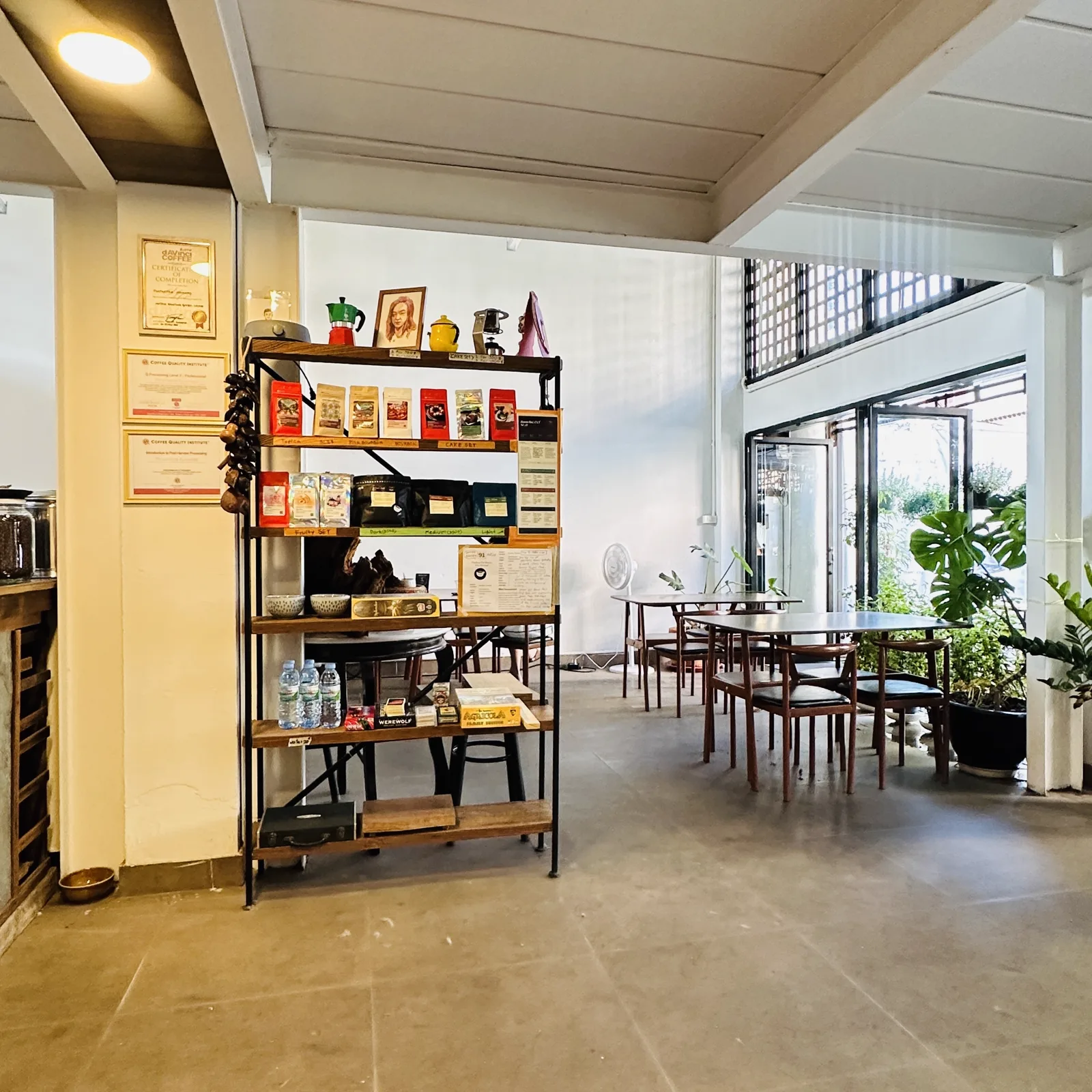 Interior with a coffee bag shelf, framed certificates and empty tables by the windows