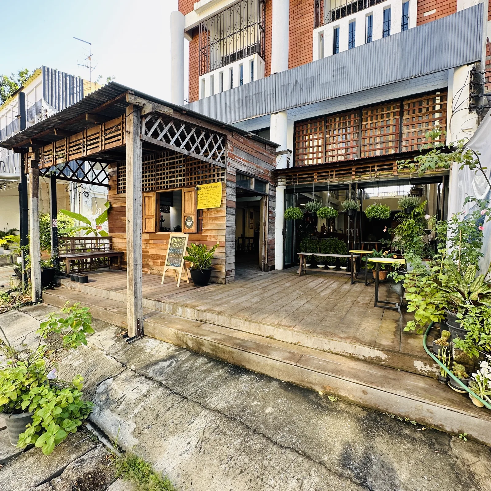 Wooden frontage with a chalkboard sign, plants and a corrugated roof