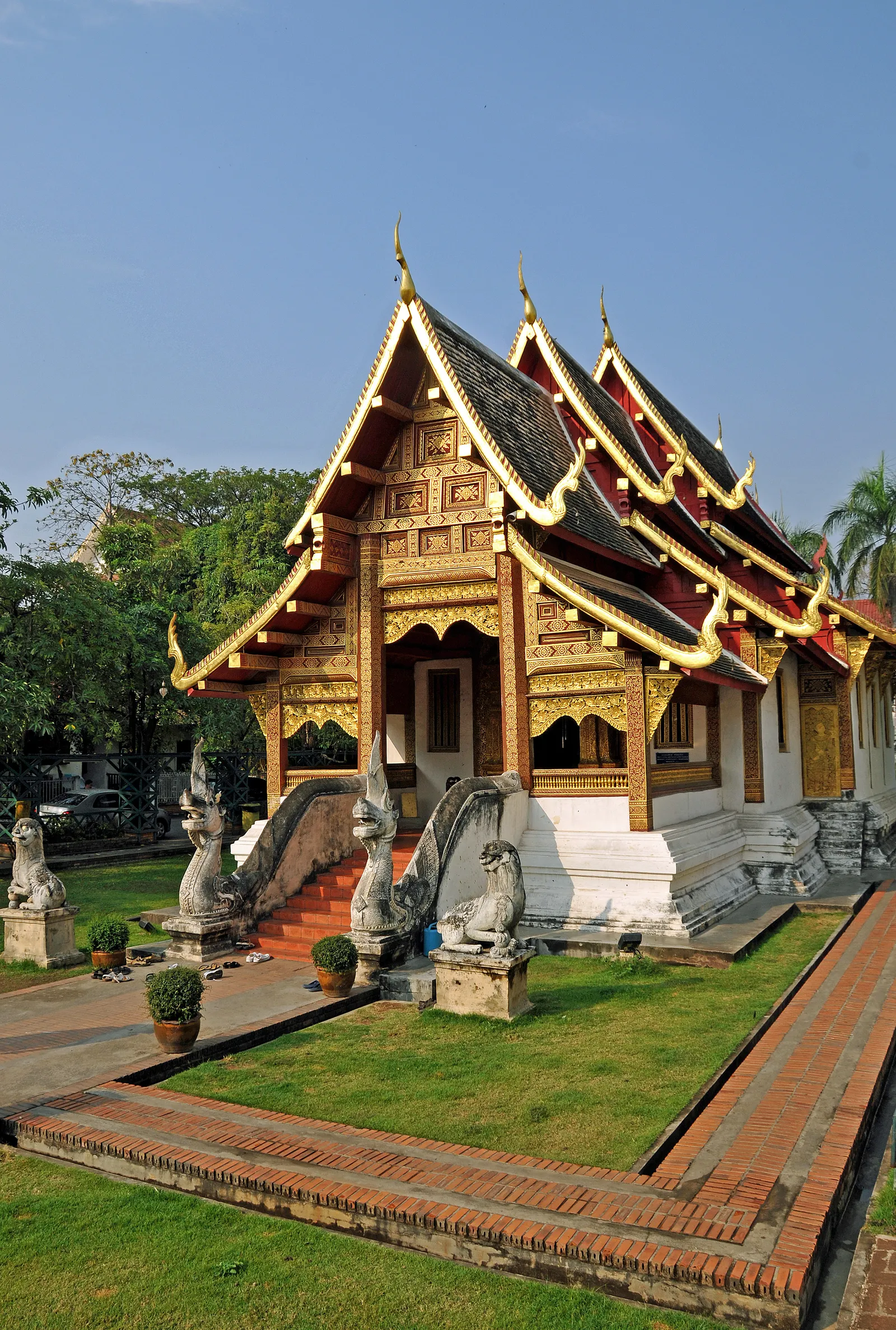 Wooden hall with a tiered roof and naga stair railings beside a lawn