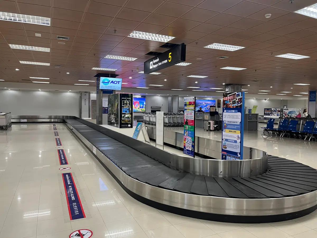 Baggage carousel with an airport operator sign hanging above it.