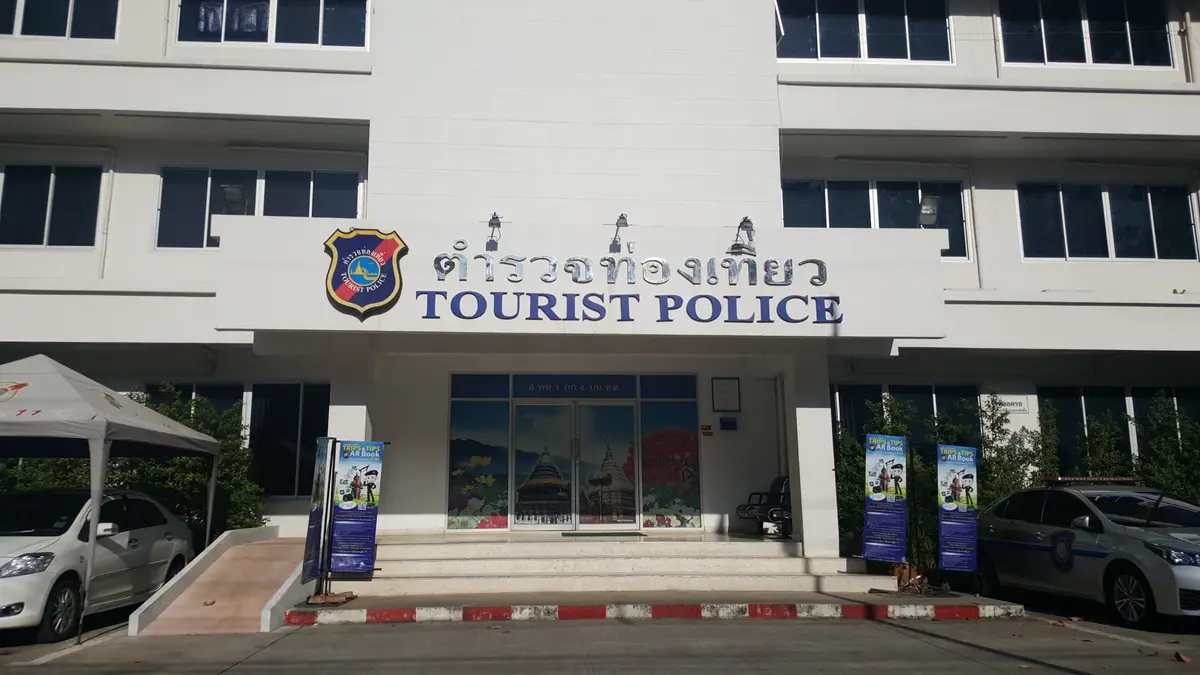 Entrance of the Tourist Police building with a sign in Thai and English and a glass door.
