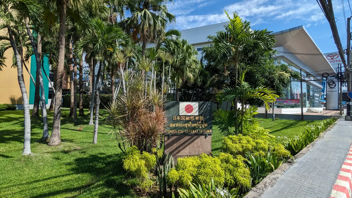Sign with a Japanese flag and the words Consulate-General of Japan among green plants