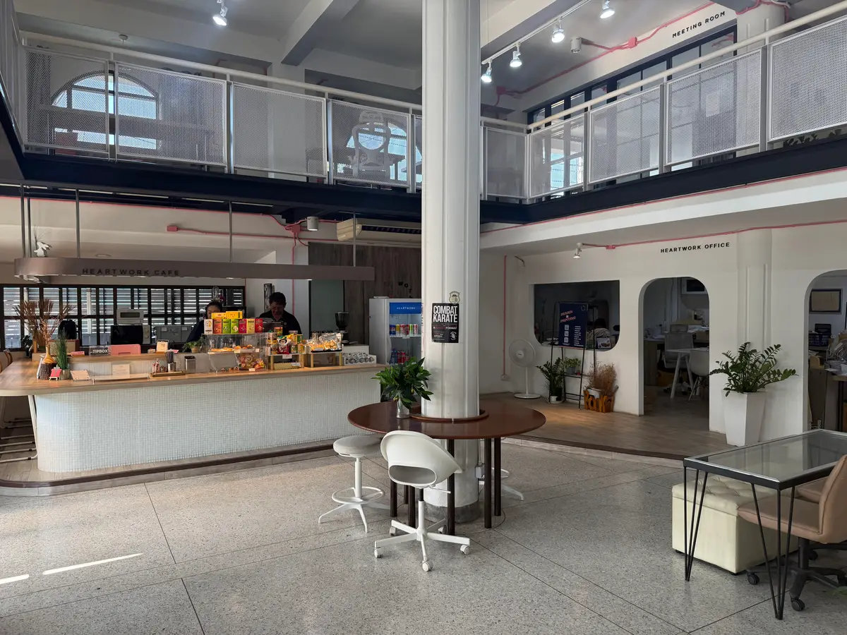 Cafe counter with stools and a shared table under a white arch in a bright hall.