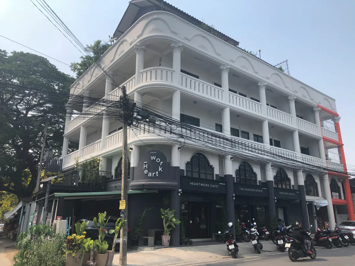 White four-storey corner building with arched windows and a cafe sign at street level.