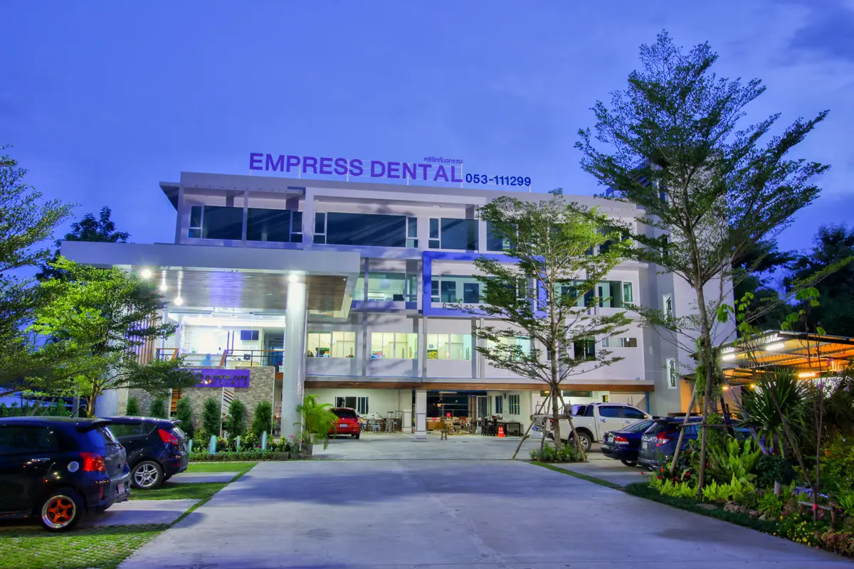 Two-storey clinic building with an Empress Dental sign lit at dusk and a car park in front