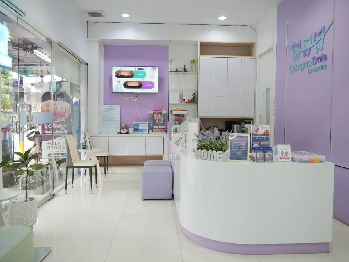 Curved white reception counter with purple accents and a wall screen in a small dental clinic