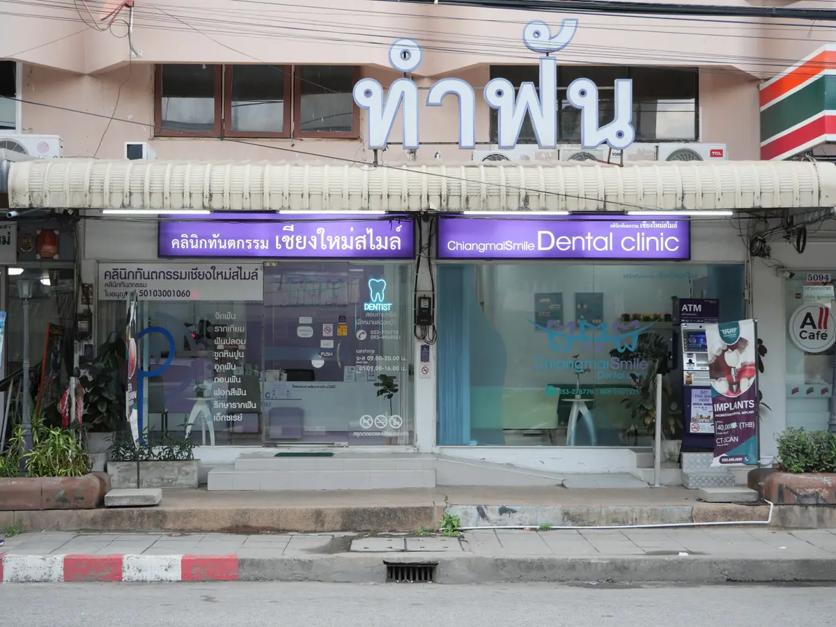 Shopfront with a purple sign for Chiangmai Smile Dental Clinic and a convenience store next door