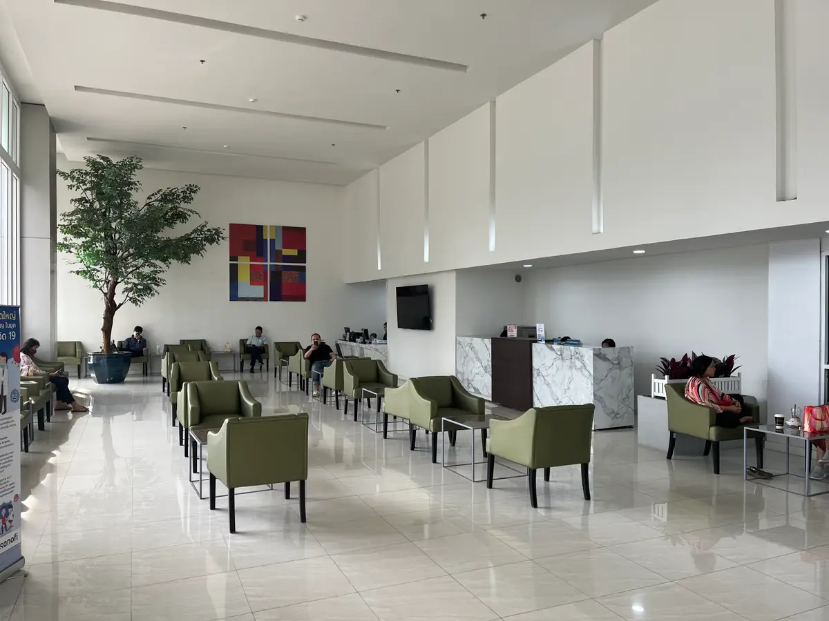 Spacious waiting hall with rows of green armchairs and a tall indoor plant