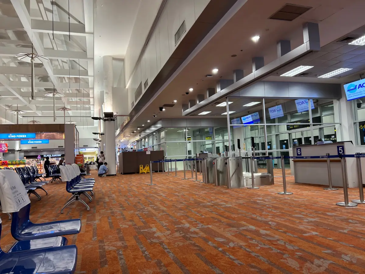 Terminal hall with blue seats on an orange carpet and counters in the background