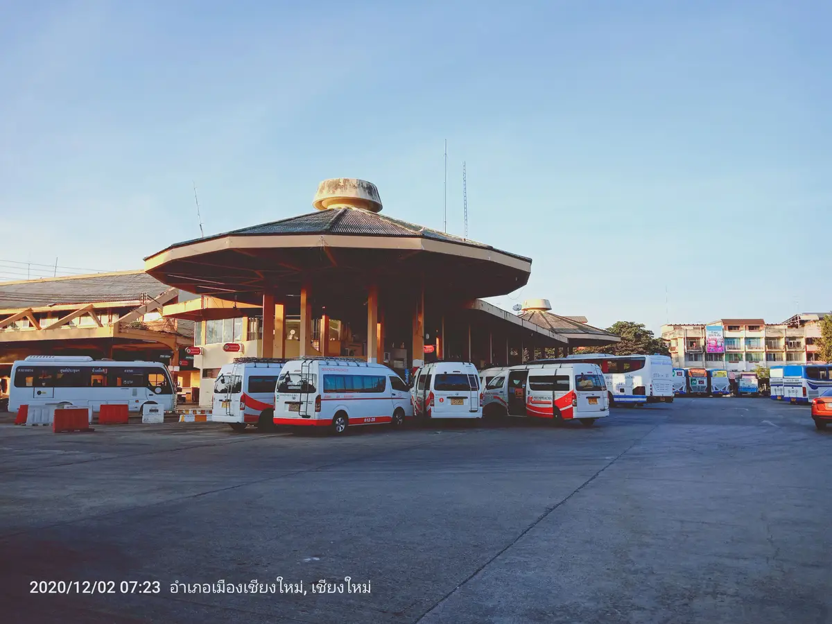 Round-roofed pavilion with white minivans parked around it under a clear sky