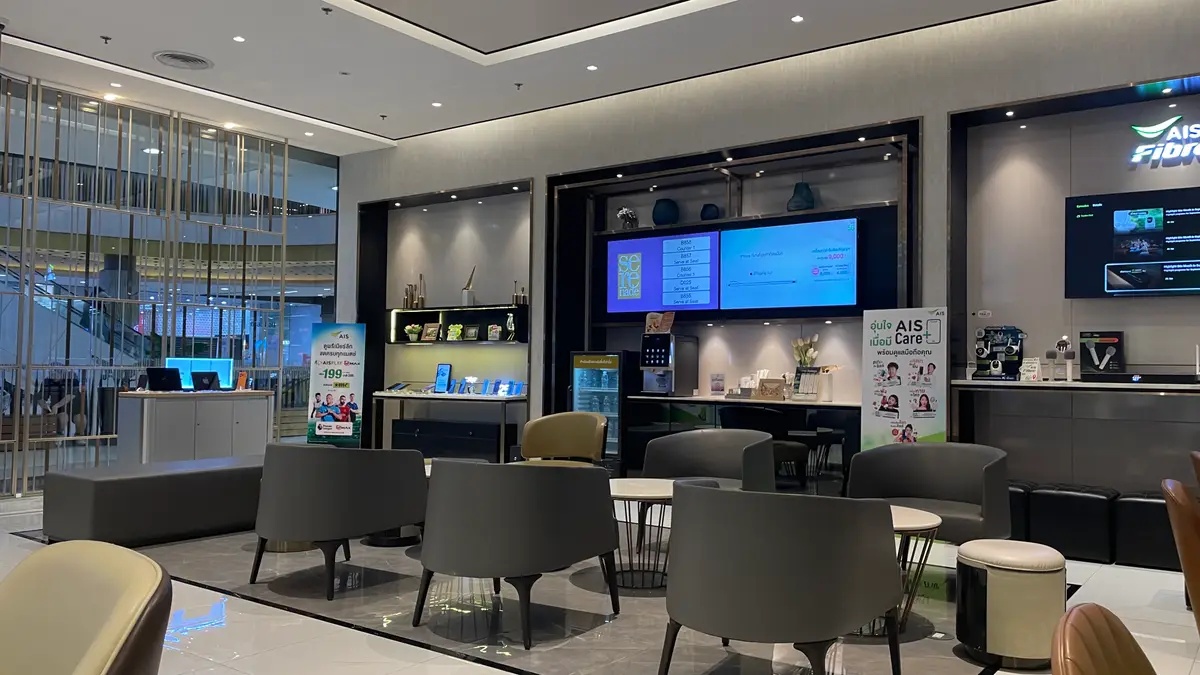 Seating area and screens inside an AIS shop with grey armchairs and a wall of displays.