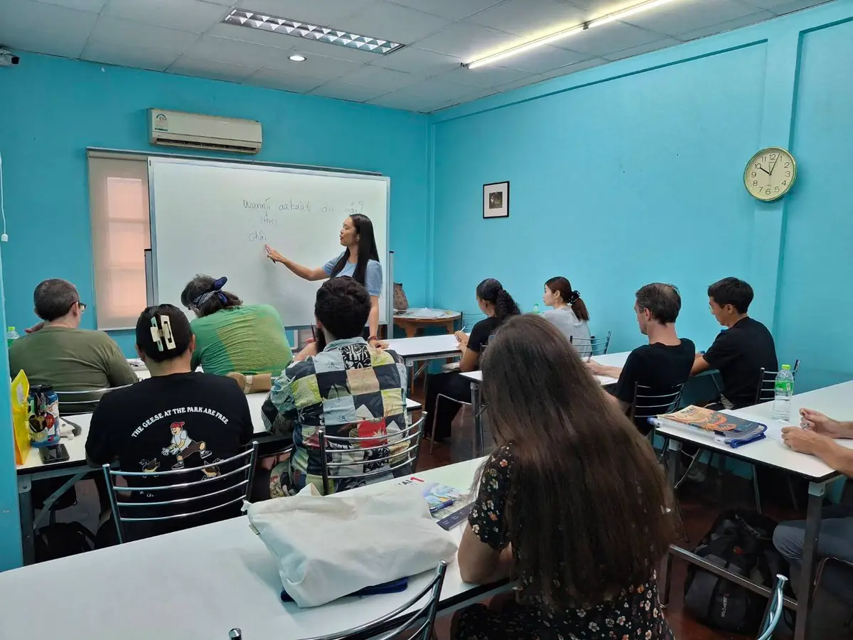 Teacher at a whiteboard in a turquoise classroom with students at desks