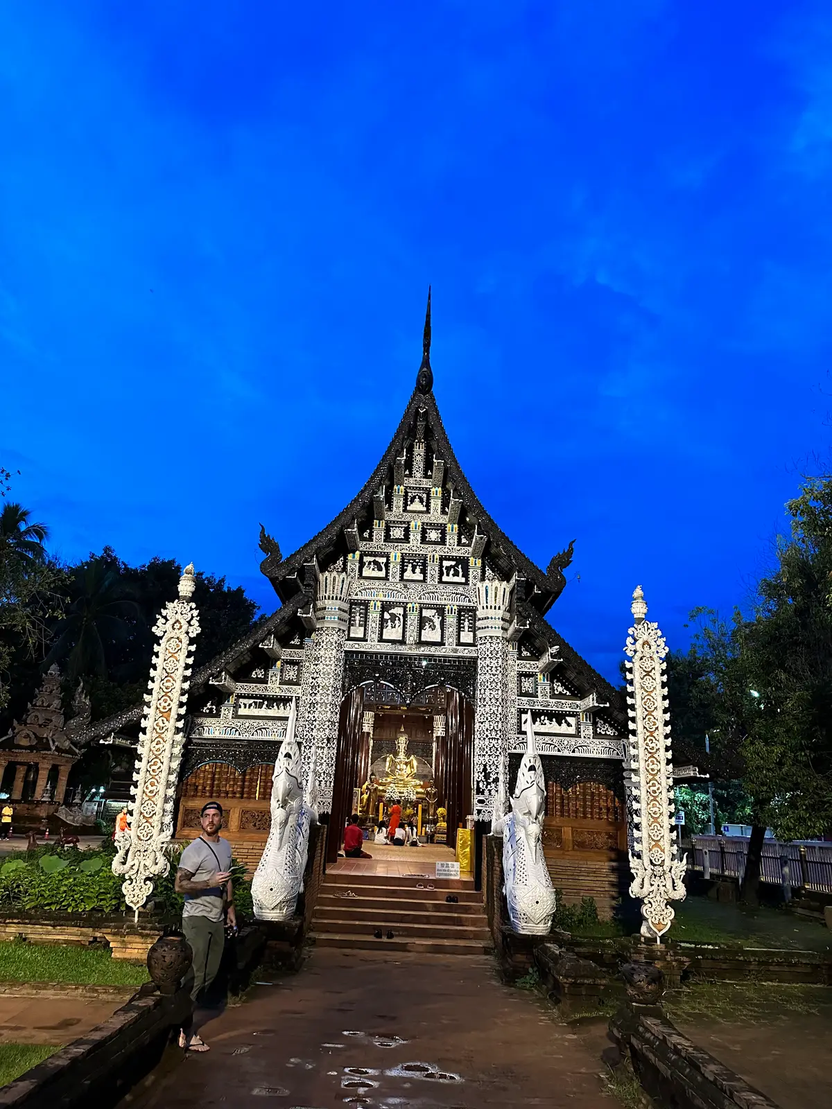 Hall front with a pointed gable, white nagas on the stair rails and a blue sky behind