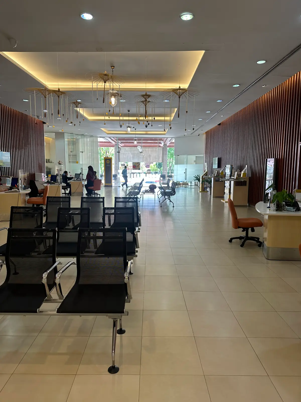 Spacious bank hall with rows of black chairs and teller desks under bright ceiling lights.