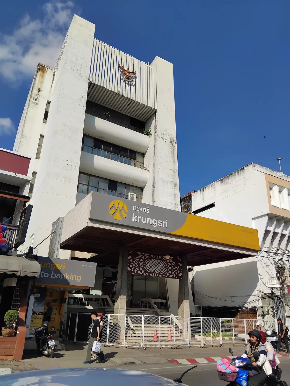 Krungsri branch entrance with a yellow sign over a covered driveway beside a white multi-storey building.