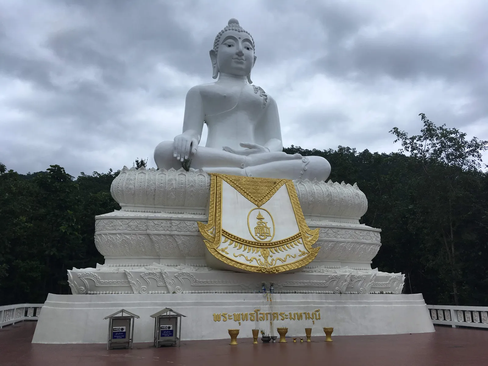 Large white seated Buddha statue on a platform under a cloudy sky
