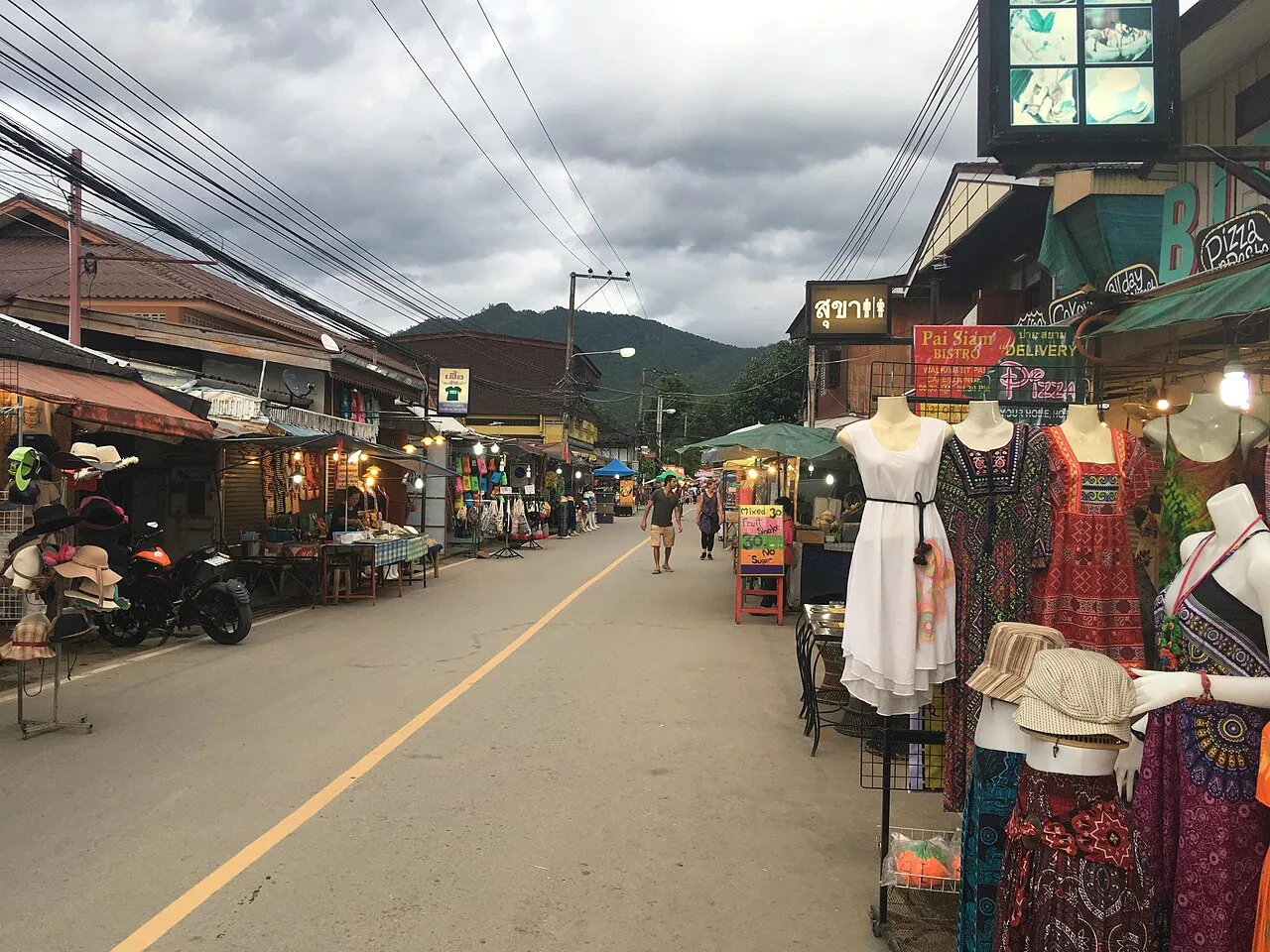 Daytime street lined with clothing stalls and shopfronts