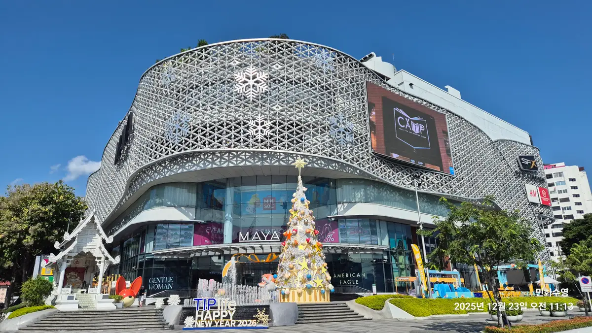 Curved white lattice facade of a large shopping centre with a Christmas tree in front