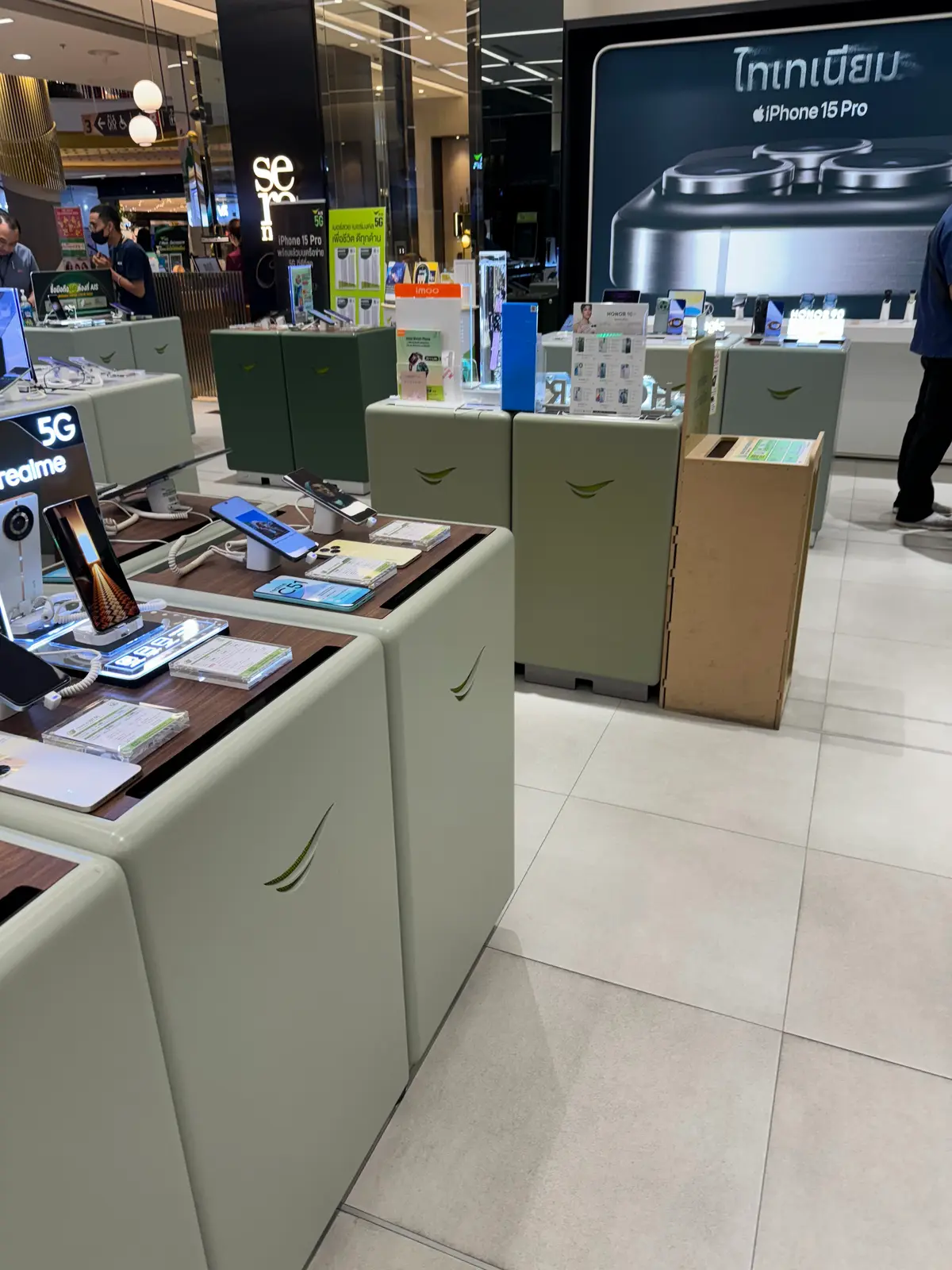 Display tables with phones and a green sales counter inside the AIS shop.