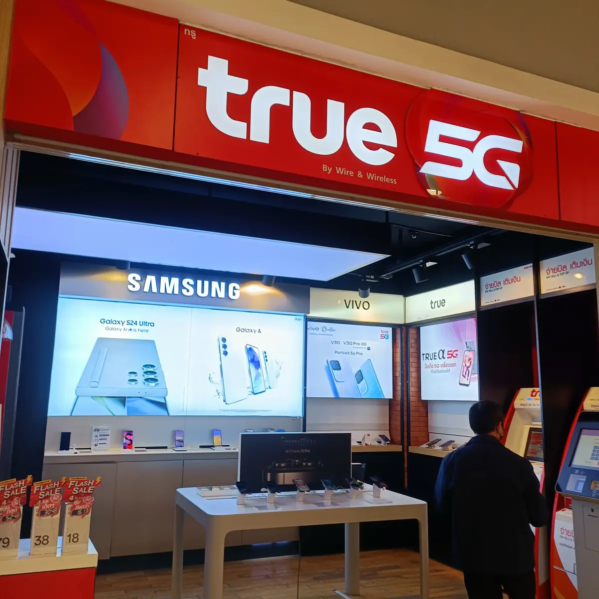 Red True shop front with the True 5G sign above shelves of phones and accessories.