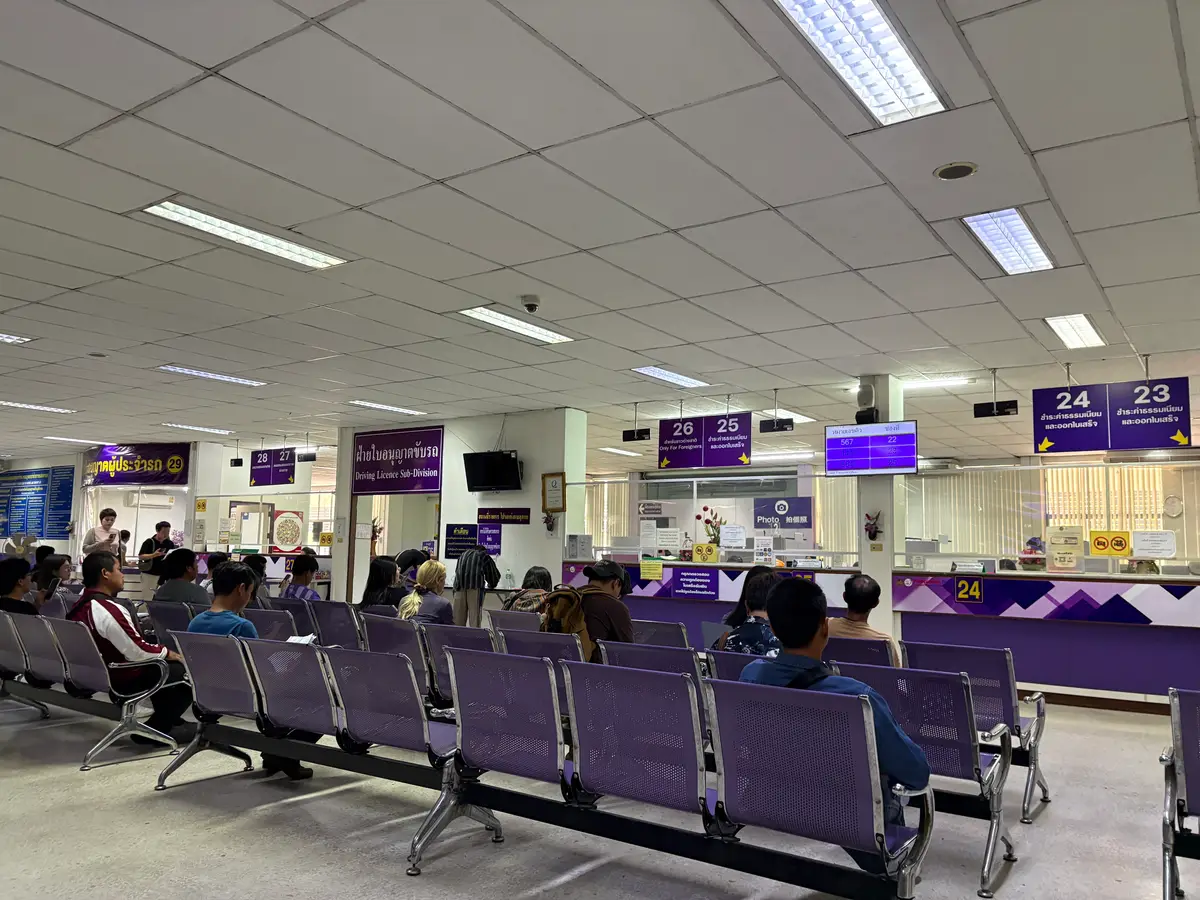 Waiting hall with rows of purple chairs and numbered queue screens above the service counters