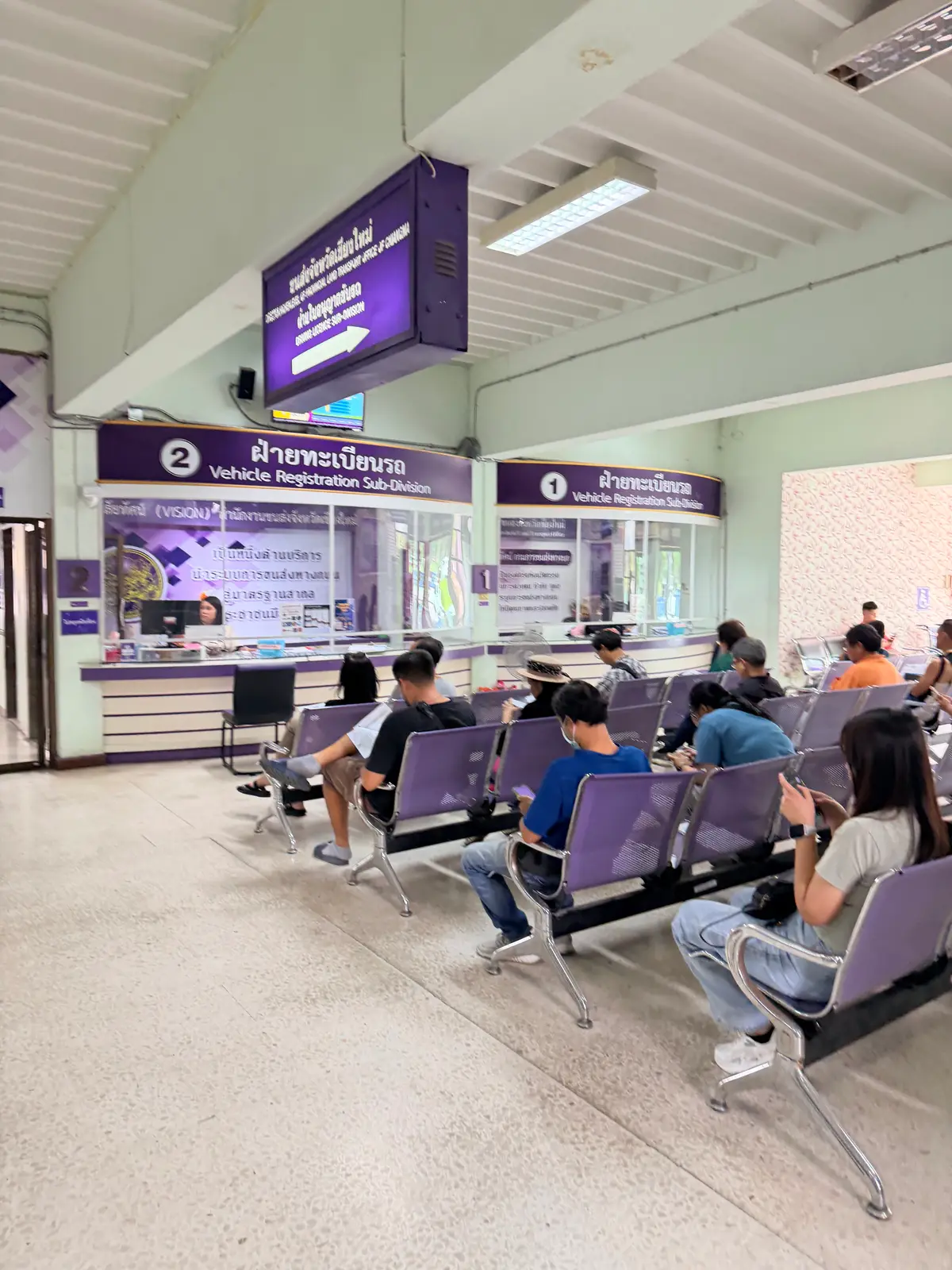 Counters and waiting chairs in a hall with signs for vehicle registration