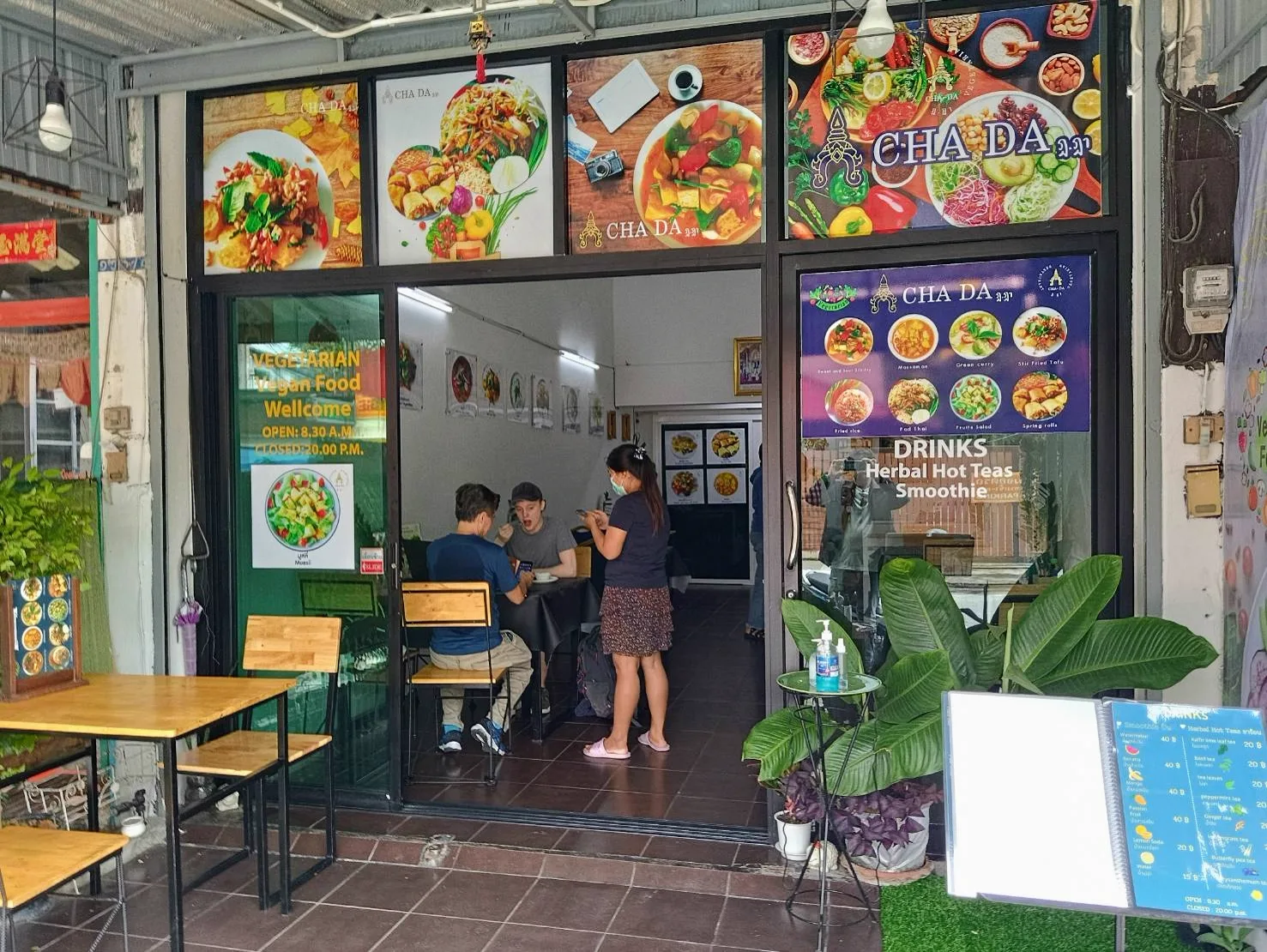 Shopfront with Cha Da signs and a vegetarian window sign, two diners visible far inside