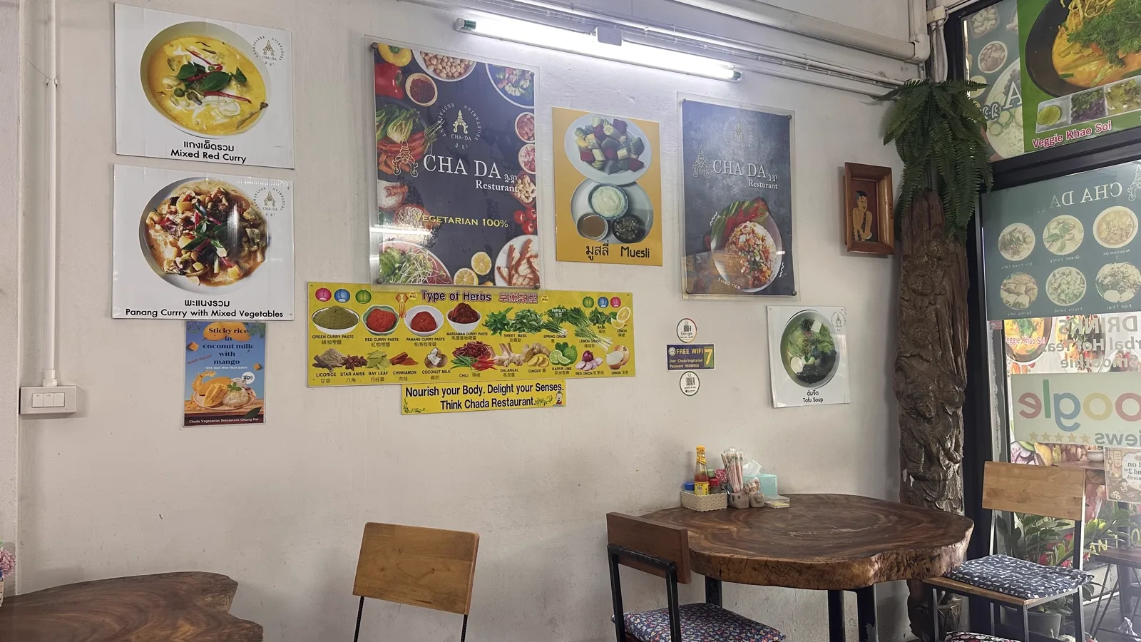 Dining room wall with framed Cha Da posters, a wooden table and chairs