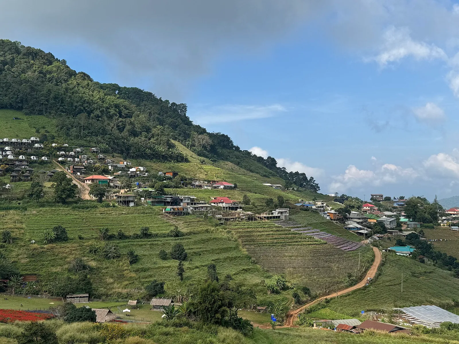 Terraced fields and village houses on a green hillside under a cloudy sky